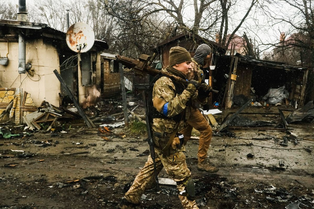BUCHA, UKRAINE - 2022/04/03: Ukrainian soldiers inspect the wreckage of a destroyed Russian armored column on the road in Bucha, a suburb north of Kyiv. As Russian troops withdraw from areas north of Ukraine's capital city of Kyiv, Ukrainian forces and the media found evidence of significant numbers of civilian casualties. The Ukrainian authorities are calling the killing of civilians in Bucha and other areas a war crime. (Photo by Matthew Hatcher/SOPA Images/LightRocket via Getty Images)