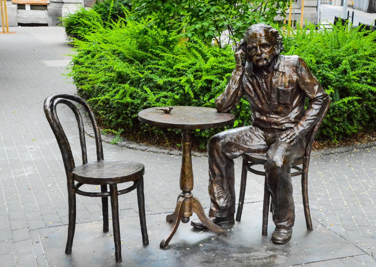 Śląskie. Pomnik Bohdana Smolenia przedstawia artystę siedzącego na krześle przy stoliku, drugie z krzeseł zaprasza do "rozmowy".