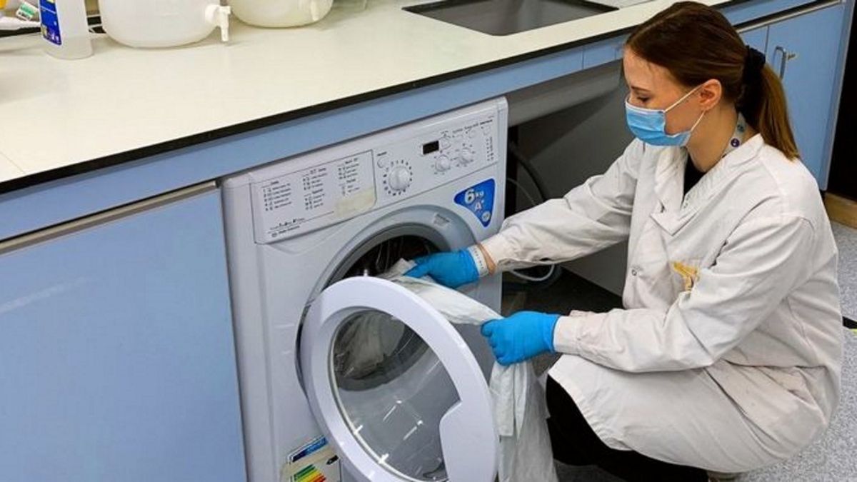 Badaczka wkłada odzież do pralki