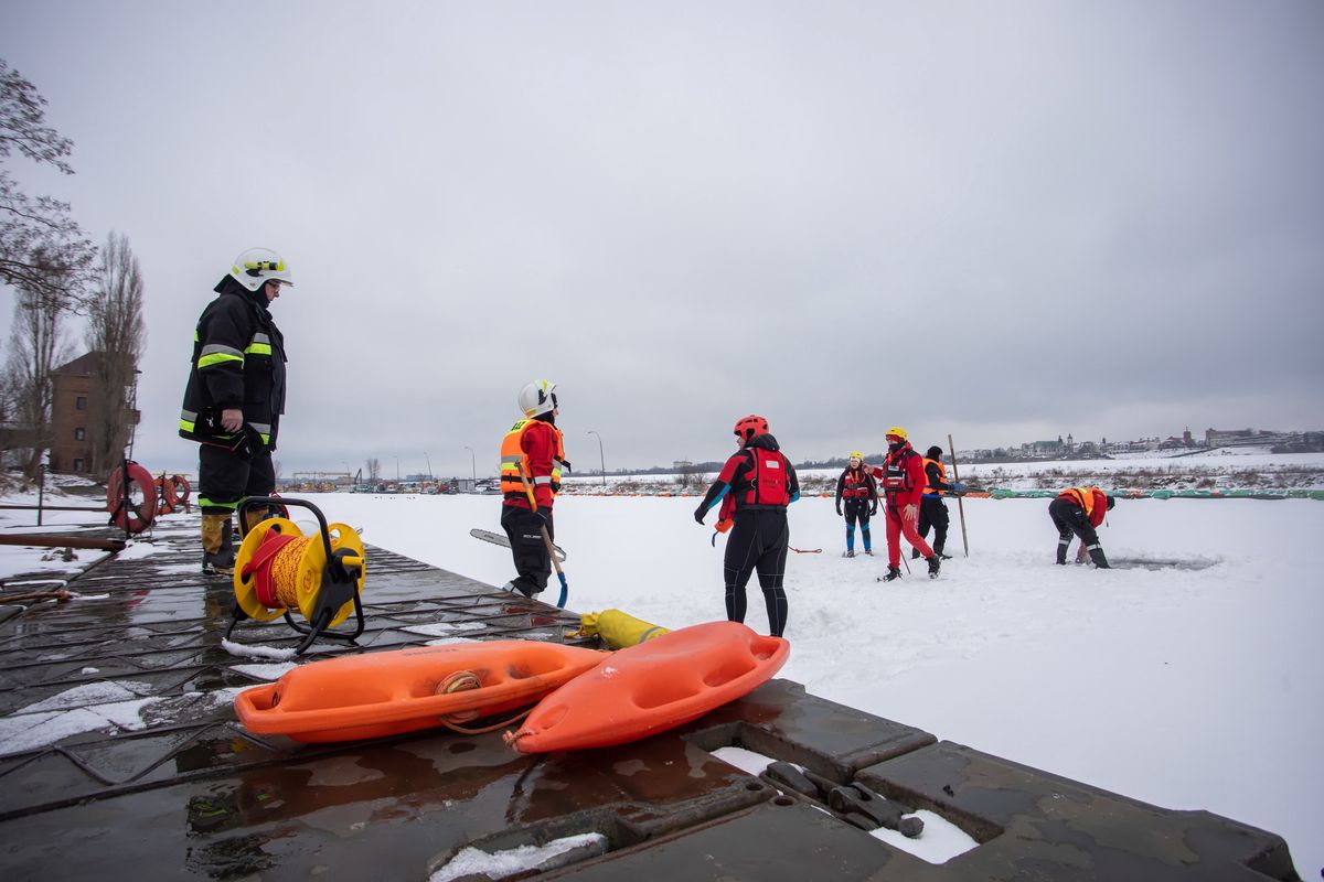 Płock. Strażacy oraz WOPR-owcy podczas akcji wykonywania otworów w pokrywie lodowej w basenie portowym w Płocku