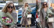 Stylowa Agnieszka Kaczorowska posyła uśmiechy do fotografa, wędrując po stolicy z bukietem kwiatów