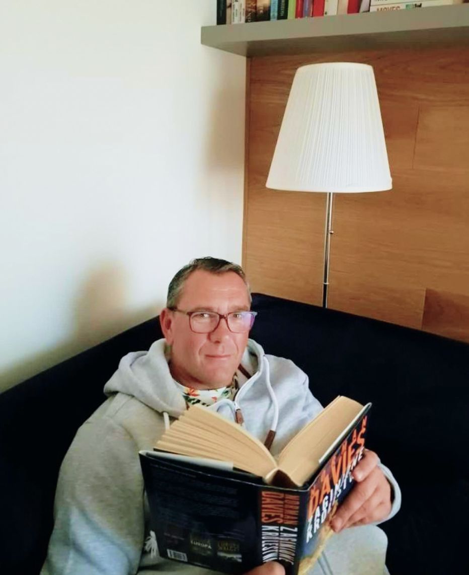 Darek Stolarz czyta książkę w salonie