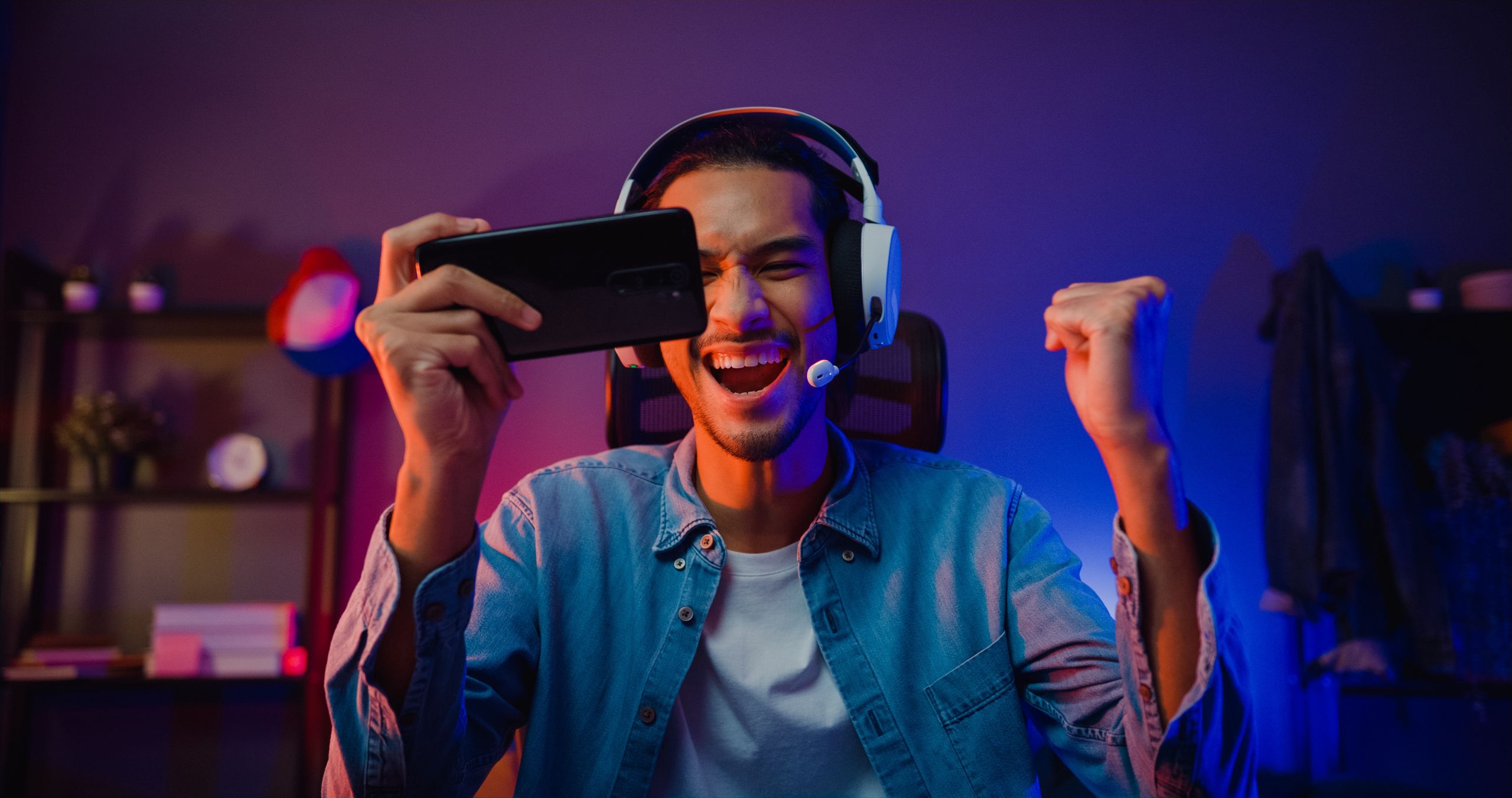 Happy asia man gamer wear headphone competition play video game online with smartphone colorful neon light in living room at night modern house. Esport streaming game online, Home quarantine activity.
game, play, phone, asian, gamer, stream, esport, online, livestream, smartphone, teenager, entertainment, headphones, man, technology, internet, broadcast, chat, male, player, vlogger, young, guy, happy, neon, victory, cybersport, win, excited, microphone, live, home, headset, mobile, cyber, action, person, adult, fun, competition, digital, hobby, room, talk, joy, smile, night, latin, indian, millennial