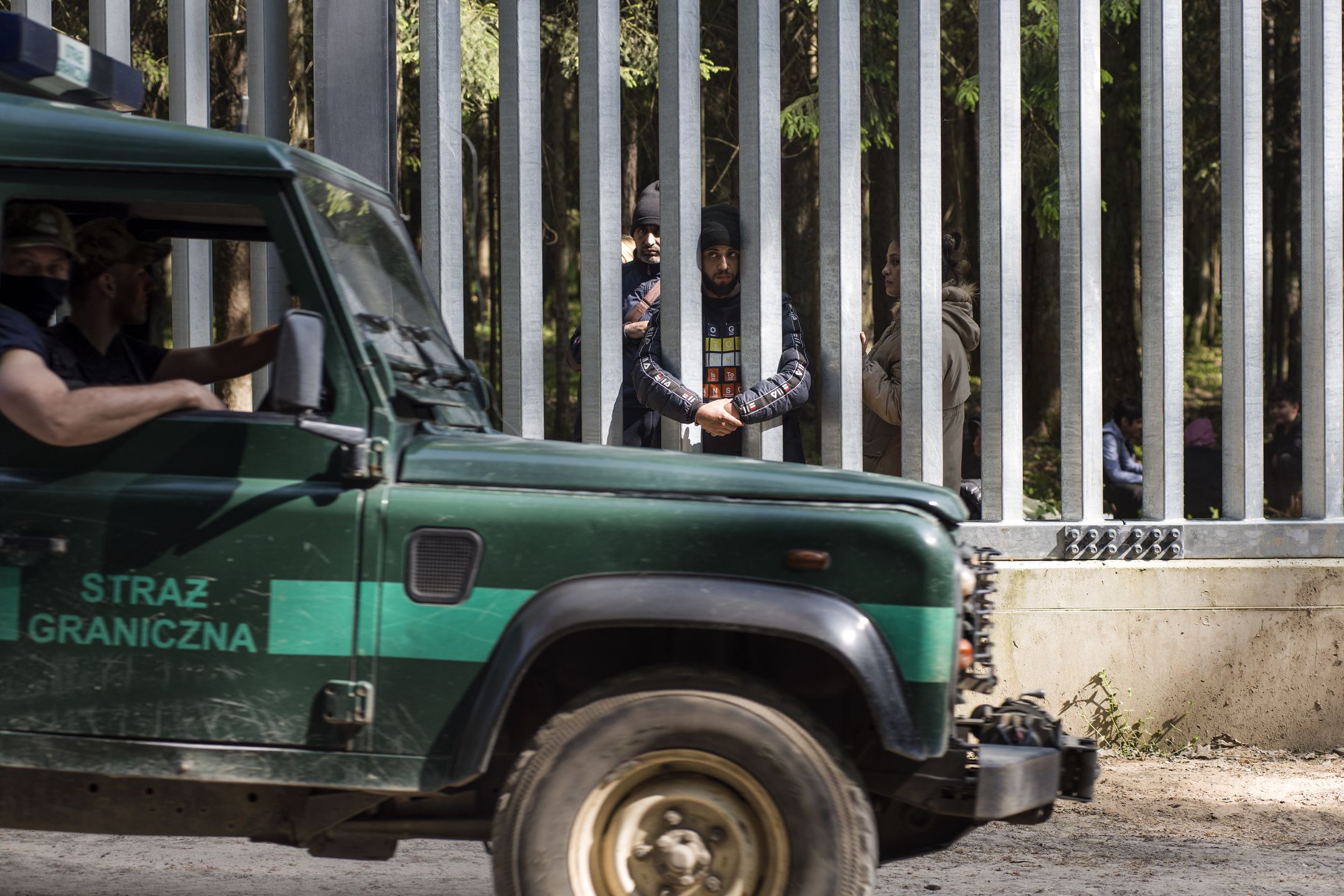 Polska Straż Graniczna mija migrantów, którzy utknęli na przejściu granicznym z Białorusią, 28 maja 2023 r.