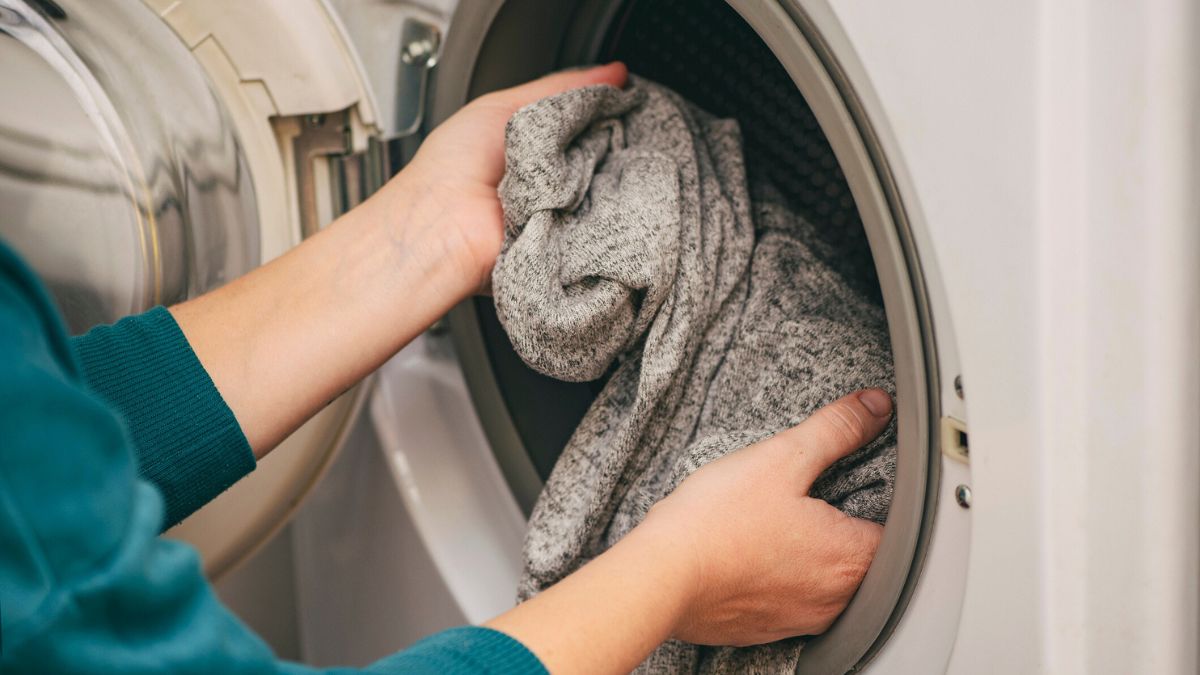 Kobieta wkłada sweter do pralki