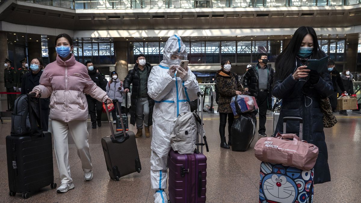 BEIJING, CHINA - JANUARY 20: A traveller wears PPE as she and others look for information on a display as the arrive to board trains on their way home for the Chinese Lunar New Year and Spring Festival at Beijing West Station on January 20, 2023 in Beijing, China. Millions of Chinese travellers are headed home for the Chinese New Year of the Rabbit on January 22, the first since China dropped its strict zero Covid policy late last year. Health officials are concerned that the holiday could cause new surges of COVID-19, especially in rural areas where medical care is often less adequate than in the larger cities where officials say the outbreaks have recently peaked. (Photo by Kevin Frayer/Getty Images)