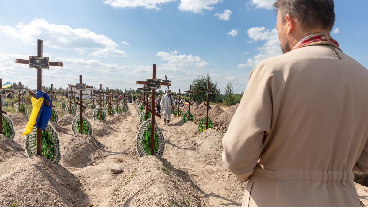 BUCHA, UKRAINE - 2022/09/02: A priest is seen reading a prayer for the repose of the souls of the innocent victims of Russian aggression. Burial of the remains of 13 unidentified and two identified people who were killed in the Buchan district during the Russian occupation. A few months after the de-occupation of the Bucha district, those bodies that were not identified were buried and marked with numbers at the cemetery in Bucha. According to the deputy mayor of Buch Mykhailyna Skoryk, a total of 419 people who were killed during the Russian occupation of the Buchan district were buried in the city. (Photo by Mykhaylo Palinchak/SOPA Images/LightRocket via Getty Images)