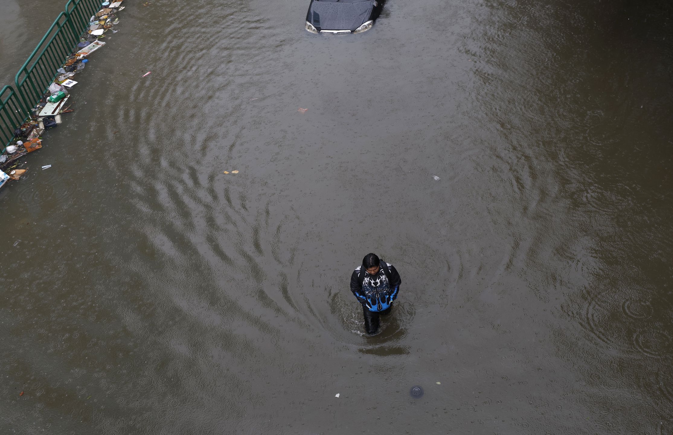 A man wades through floodwater next to a submerged abandoned car during a downpour on a flooded major street, Phetchaburi Road in Bangkok, Thailand, 26 September 2026. All 50 districts in Bangkok have been declared flood disaster zones following the non-stop heavy downpour caused by a strong low-pressure system combined with seasonal monsoon patterns. EPA/RUNGROJ YONGRIT Dostawca: PAP/EPA.