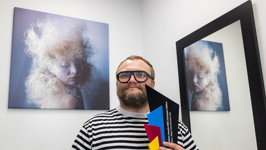 Bydgoski fryzjer Mikołaj Drozdowski do startu w konkursach międzynarodowych wrócił po dłuższej przerwie. Na zdjęciu ze statuetką, w tle zdjęcie zwycięskiej fryzury.