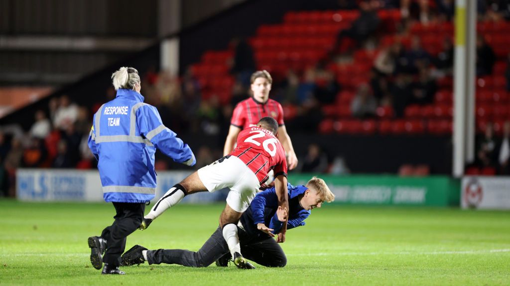 Getty Images / Plumb Images/Leicester City FC  / David Okagbue zatrzymuje kibica biegnącego w stronę trenera Leicester - Steve'a Coopera