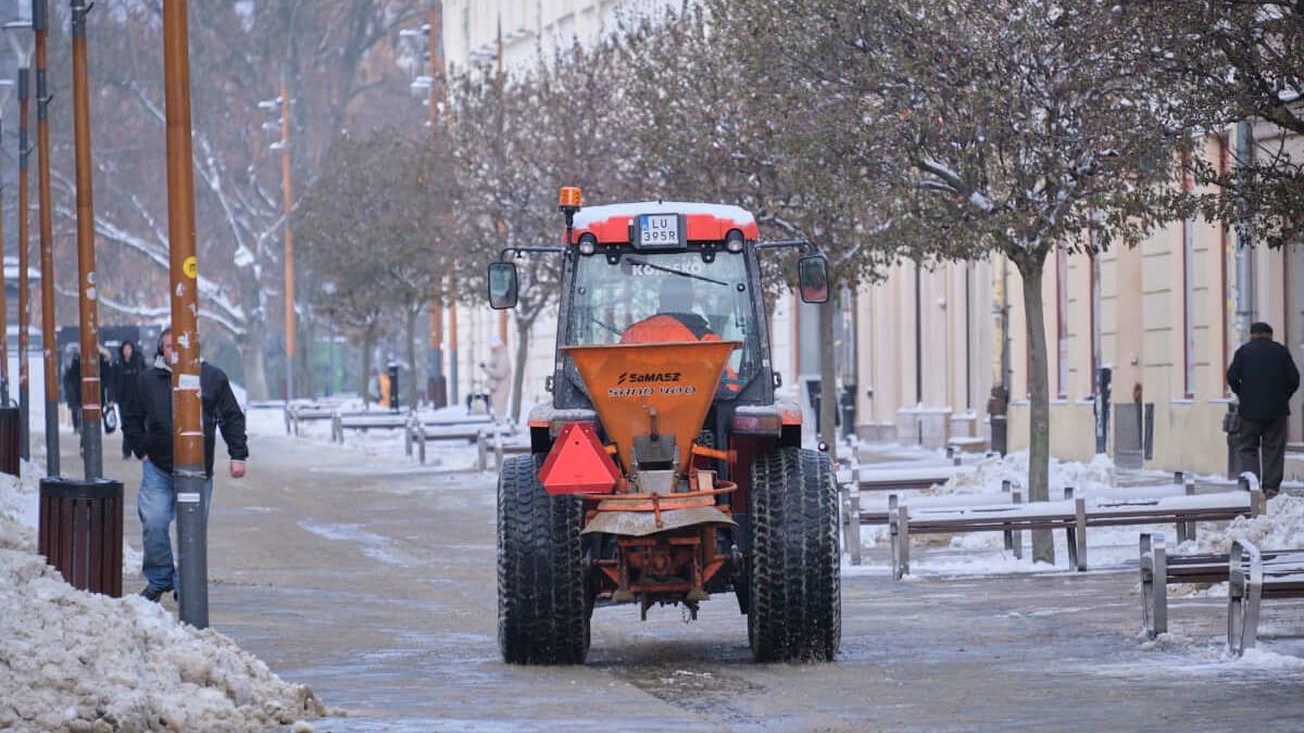Opłużony ciągnik posypujący piasek na deptaku w Lublinie