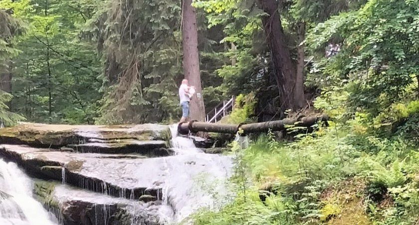 Turysta z dzieckiem na rękach na skraju wodospadu. "To szaleństwo"