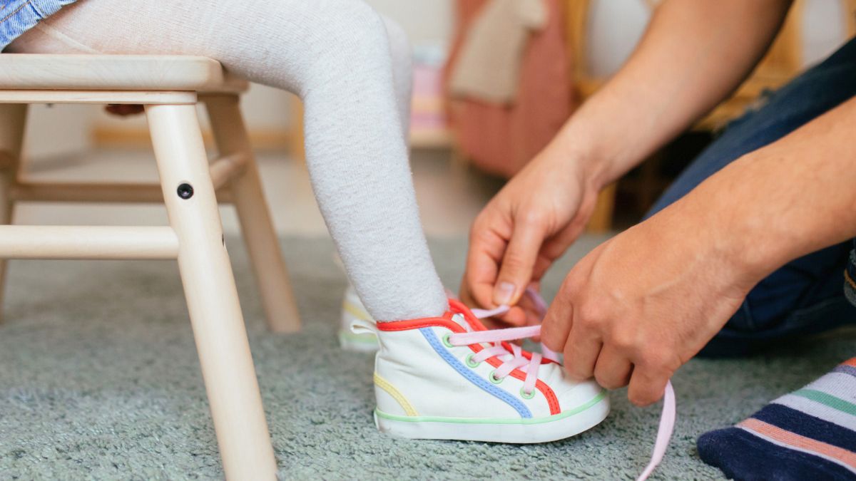 Kobieta zawiązuje dziecku buty