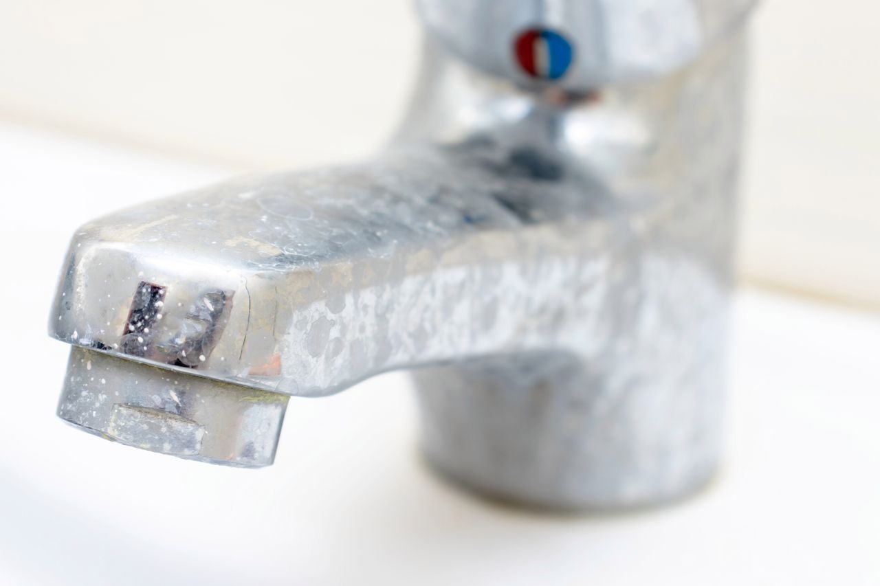 Dirty faucet with limescale, calcified water tap with lime scale on washbowl in bathroom.