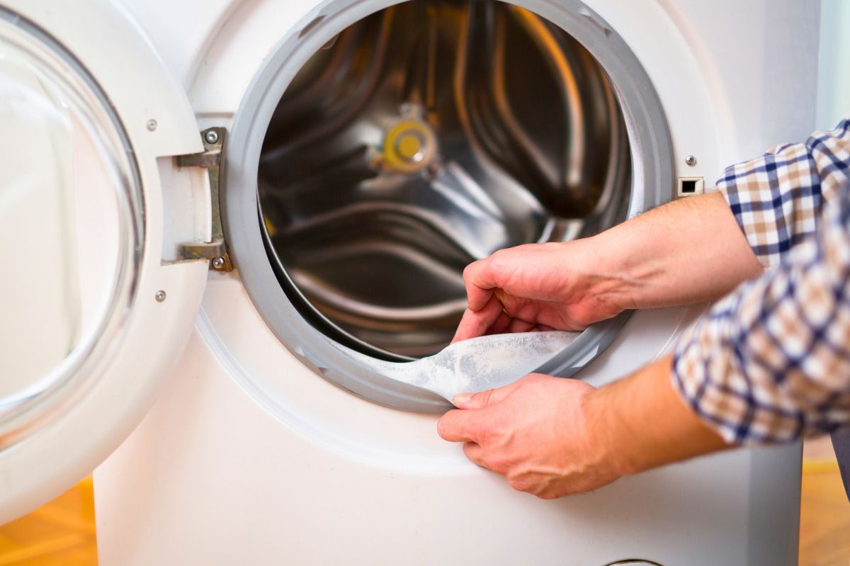 The man is cleaning the washing machine.