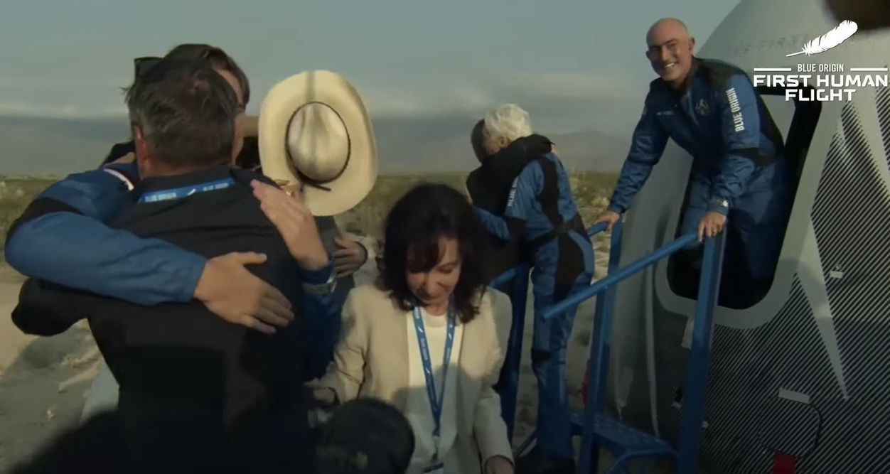 Jeff Bezos (z prawej) wychyla się z kapsuły statku kosmicznego, którym przed chwilą wrócił na Ziemię