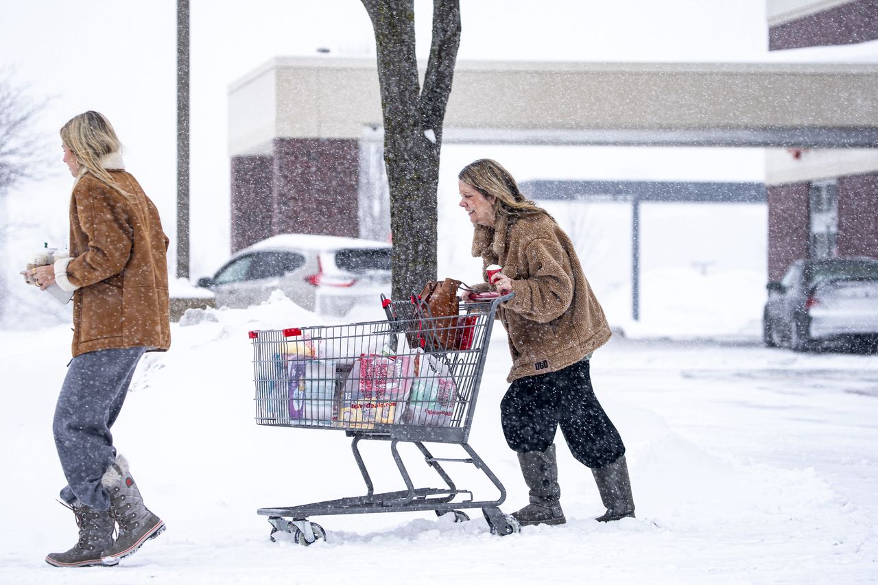 Shoppers push a cart of groceries through snow during a winter storm ahead of the Iowa caucus in West Des Moines, Iowa, US, on Friday, Jan. 12, 2024. The polar vortex is about to unleash an Arctic chill across much of the US this weekend, leaving football fans shivering in the Midwest and inflicting subzero temperatures on Iowa voters just before the states caucus begins. Photographer: Al Drago/Bloomberg via Getty Images