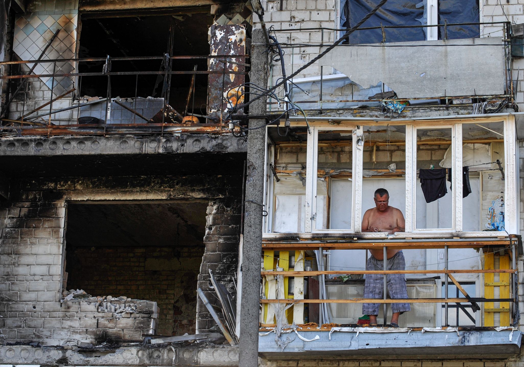 Mężczyzna na balkonie zniszczonego budynku w Makarowie. Zdjęcie zostało zrobione po wycofaniu się Rosjan (Photo by Sergei Chuzavkov/SOPA Images/LightRocket via Getty Images)