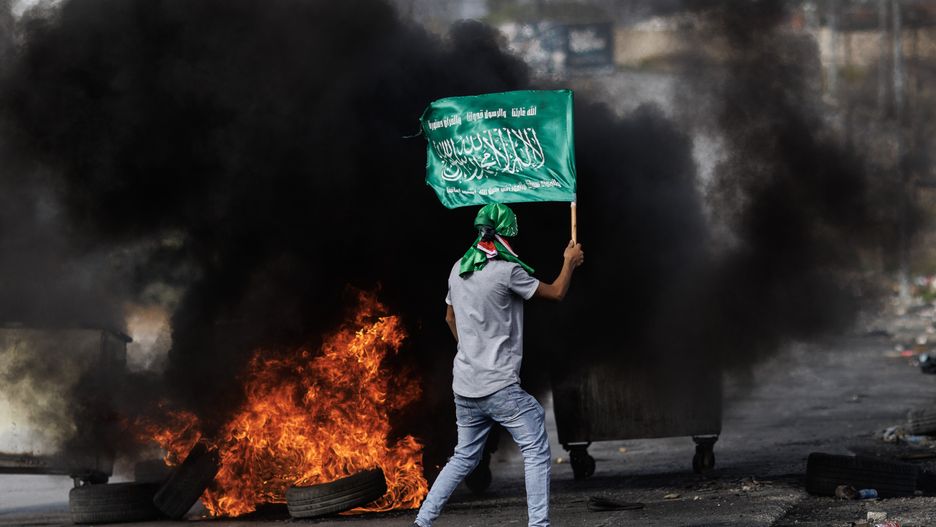 RAMALLAH, WEST BANK - OCTOBER 27: Palestinian youths waving Hammas flags clash with Israeli Defence Forces during skirmishes at a checkpoint on October 27, 2023 in Ramallah, West Bank. The Ramallah-based health ministry said that over a 100 Palestinians have died in the West Bank since Oct. 7, when war erupted between Israel and Hamas, the Palestinian militant group that rules the Gaza Strip. Many of the deaths in the West Bank, which is governed by the rival Palestinian Authority, have come during Israeli raids, authorities here said. Others have been killed in clashes with Israeli settlers. (Photo by Dan Kitwood/Getty Images)