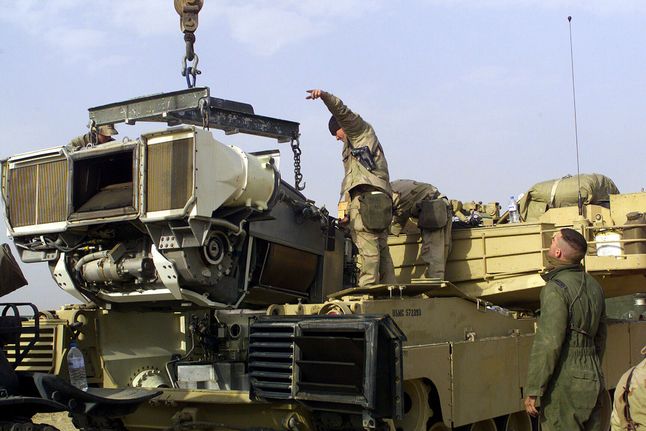 Żołnierze Marines montują turbinę AGT-1500 do czołgu M1 Abrams w Kuwejcie w 2003 r.