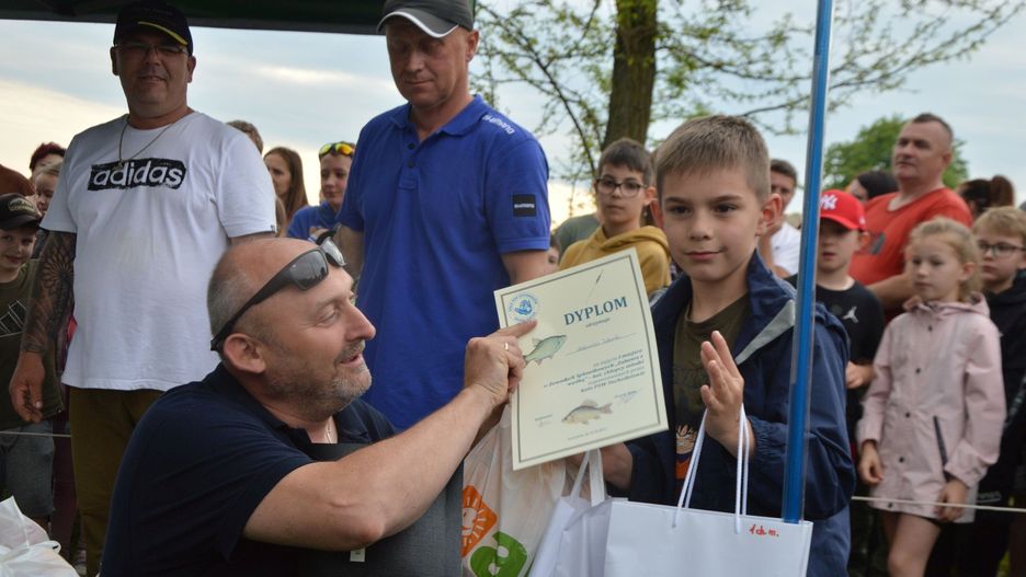 Kamil Kutwin, zwycięzca zawodów wędkarskich &#34;Zabawa z wędką&#34; w kategorii chłopców starszych odbiera nagrody z rąk prezesa koła PZW w Suchedniowie Rafała Kutwina.