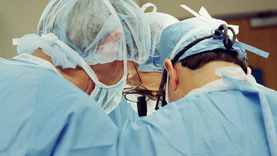 Three surgeons operating on heart, upper section, rear view