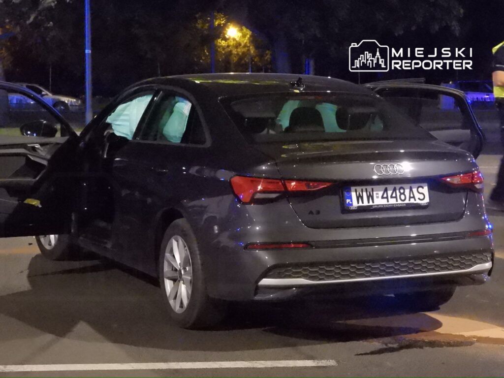 Czarny samochód marki Audi A3 z otwartymi drzwiami, zaparkowany na ulicy w nocy.