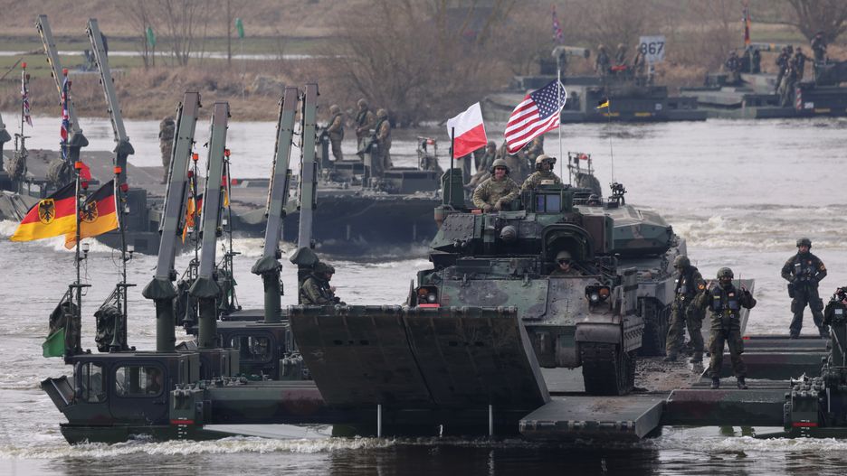 GNIEW, POLAND - MARCH 04: A Bradley infantry fighting vehicle of the U.S. Army rides M3 amphibious rigs of the German/British Amphibious Engineer Battalion 130 while crossing the Vistula River during the NATO Dragon 24 military exercise on March 04, 2024 near Gniew, Poland. Dragon 24 is involving 20,000 troops from 10 different nations and is part of Steadfast Defender 2024, an ongoing set of NATO military manoeuvres across Europe that is involving 90,000 troops. (Photo by Sean Gallup/Getty Images)