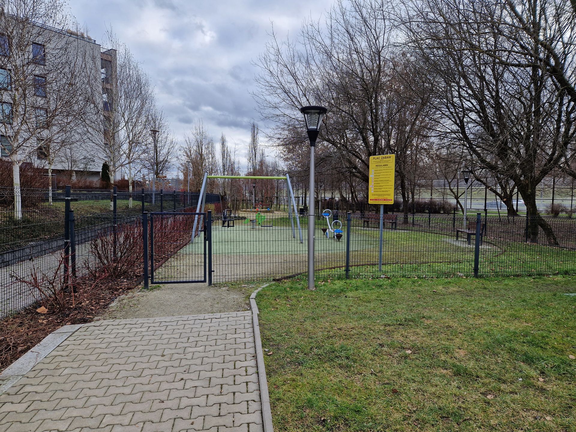 Na zdjęciu plac zabaw ogrodzony płotem