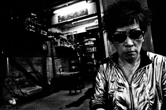 Fotograf daje nam przegląd tego co dzieje się w dzielnicy Kowloon zarówno w ciągu dnia jak i nocy. Zaczynamy od ruchliwych ulic i bazarów na których można nie tylko zrobić zakupy ale też zjeść tradycyjne dania na wolnym powietrzu. Wraz z nastaniem wieczora możemy natknąć się na pracujące dziewczyny i bezsennych narkomanów.