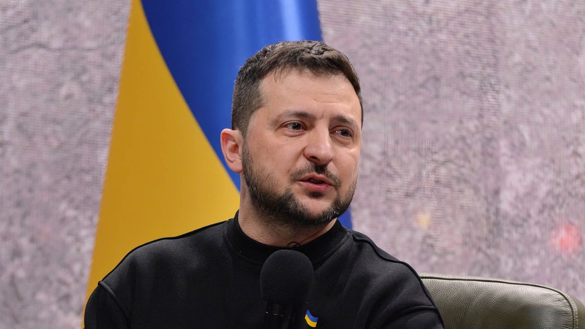 Wołodymyr Zełenski w fotelu na tle ukraińskiej flagi