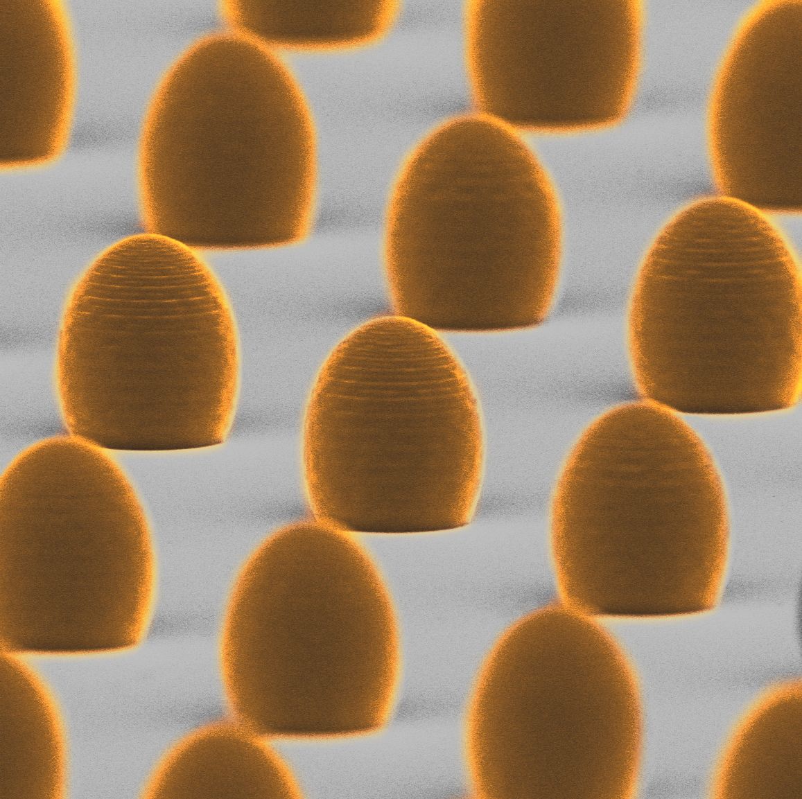 Asferyczne mikrosoczewki wydrukowane na laserowej drukarce 3D - zdjęcie z mikroskopu elektronowego. Średnica każdej z soczewek wynosi 15 mikrometrów, czyli około jednej piątej grubości ludzkiego włosa. Dzięki wysokiej wydajności druku 3D można w krótkim czasie wyprodukować setki mikrosoczewek na jednym podłożu.
