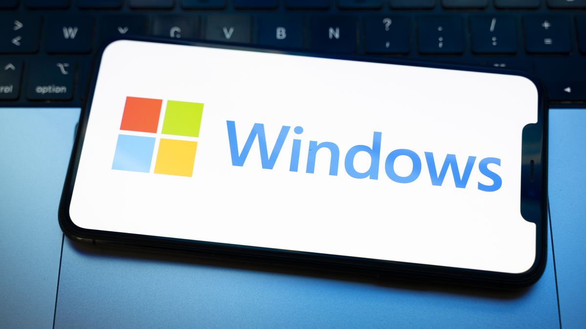 The Windows logo appears on the screen of a smartphone placed on a computer keyboard illuminated by blue and white light. Microsoft releases a major update to Windows 11 (25H2) and Windows 10 support ends permanently on October 14. In Creteil, France, on October 9, 2025. (Photo by Samuel Boivin/NurPhoto via Getty Images)