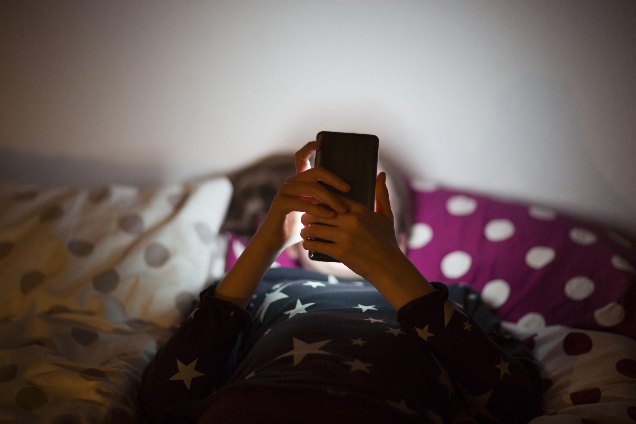 Girl lying on bed at night and using a mobile phone
Elva Etienne