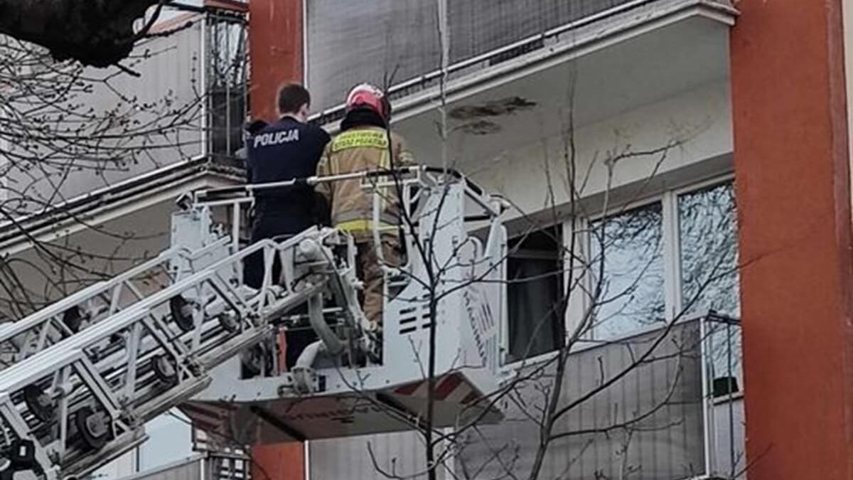 Strażak i policjant próbują wejść do zamkniętego mieszkania przez balkon