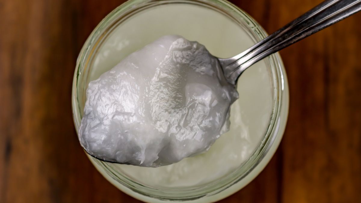 A Spoonful of Coconut OilA spoonful of coconut oil set on a jar sitting on a wooden surfacelauraagwooden surface