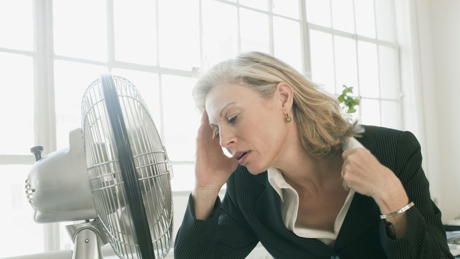 Hot businesswoman sitting in front of fan