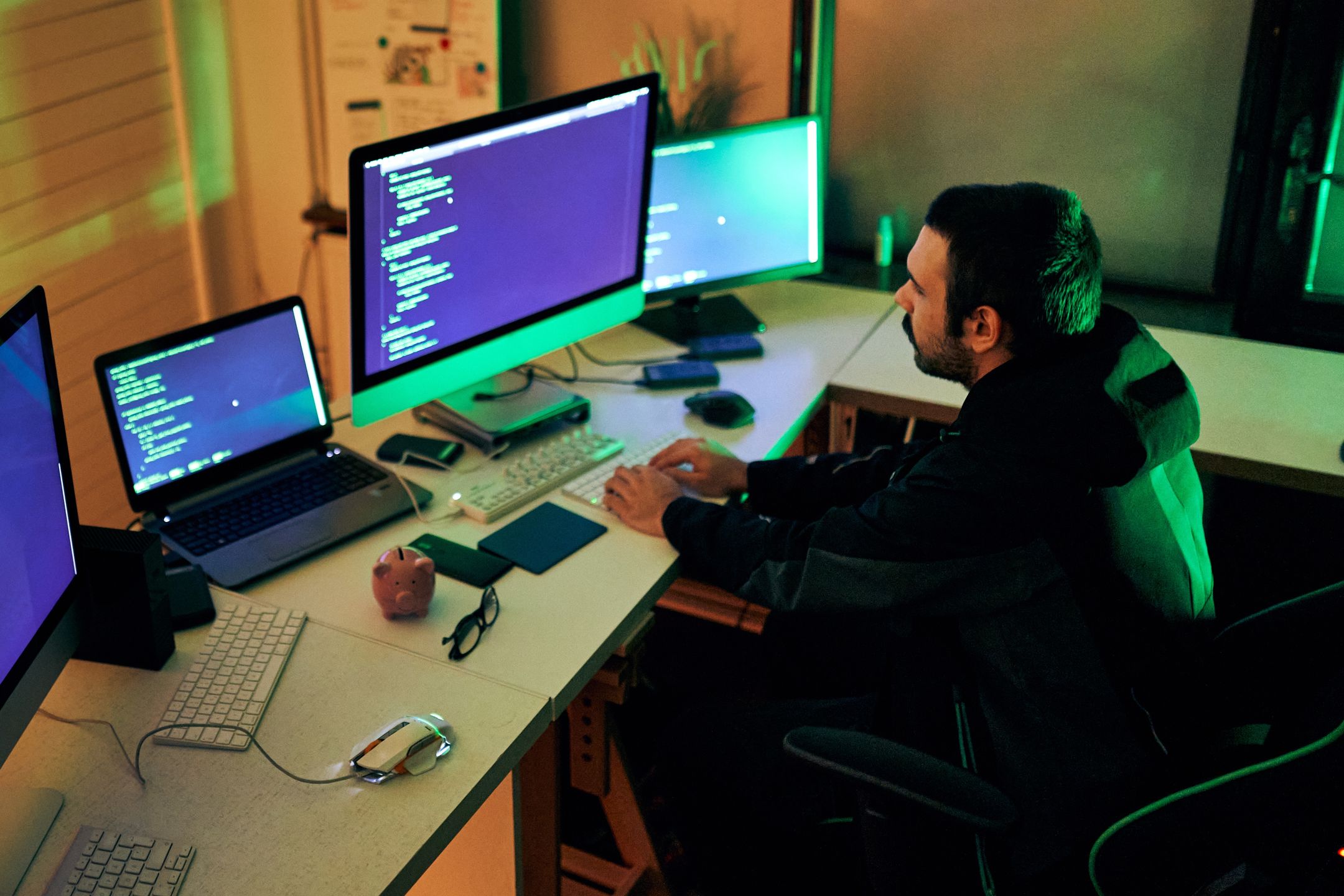 Young male hacker sitting in a room, working on his computer