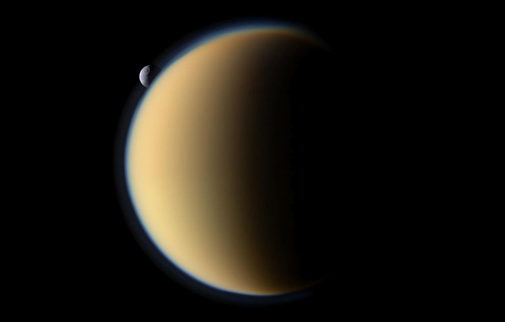 Lodowa Tetyda przemyka za największym satelitą Saturna pokrytym gęstą atmosferą Tytanem. Na powierzchni Tetydy widoczny jest krater Odyseusz o średnicy 400 km (co stanowi 2/5 średnicy całego księżyca). Zdjęcie wykonane zostało z odległości ok. 1 mln km od Tytana i ok. 2,2 mln km od Tetydy. Pojedynczy piksel odpowiada 6 km na Tytanie oraz 13 km na Tetydzie.