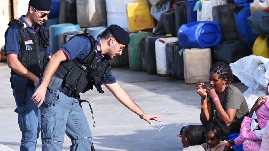 An Italian police officer interacts with a rescued migrant child blowing soap bubbles as a group waits for further registration procedures after arriving in the port of Lampedusa, 18 September 2023. More than 1,000 migrants remain in the hotspots of Lampedusa where they await transfer. Italian Deputy Premier and Foreign Minister Antonio Tajani on 15 September called for the intervention of the United Nations in response to the significant increase in the arrival of migrants and refugees by sea to Italy in recent days. EPA/CIRO FUSCO Dostawca: PAP/EPA.