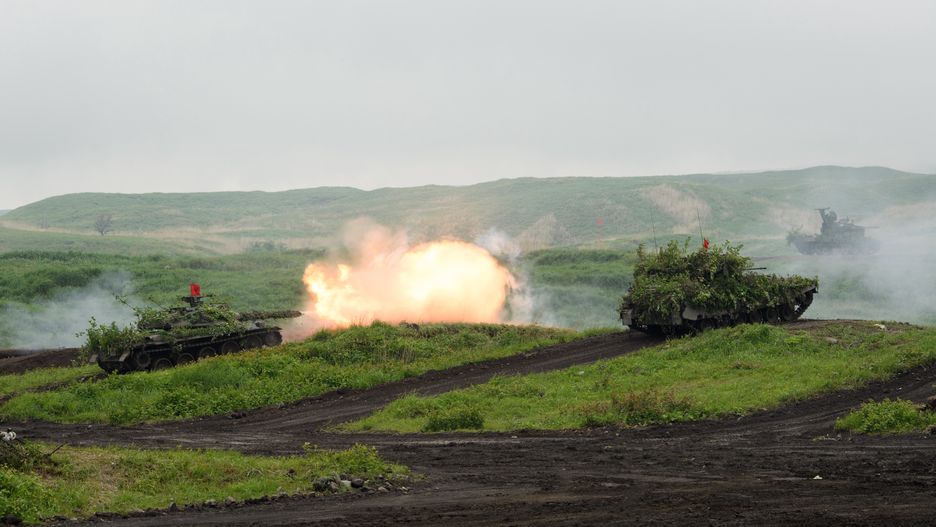 A Japan's Ground Self-Defense Forces (JGSDF) Type-74 tank, left, fires ammunition during a live fire exercise at JGSDF's training grounds in the East Fuji Maneuver Area in Gotemba, Japan, on Saturday, May 22, 2021. A key part of US President Joe Bidens foreign policy has been turning to allies for support in addressing the security risks posed by the likes of China and North Korea, placing a greater emphasis on the Indo-Pacific region. Photographer: Akio Kon/Bloomberg via Getty Images