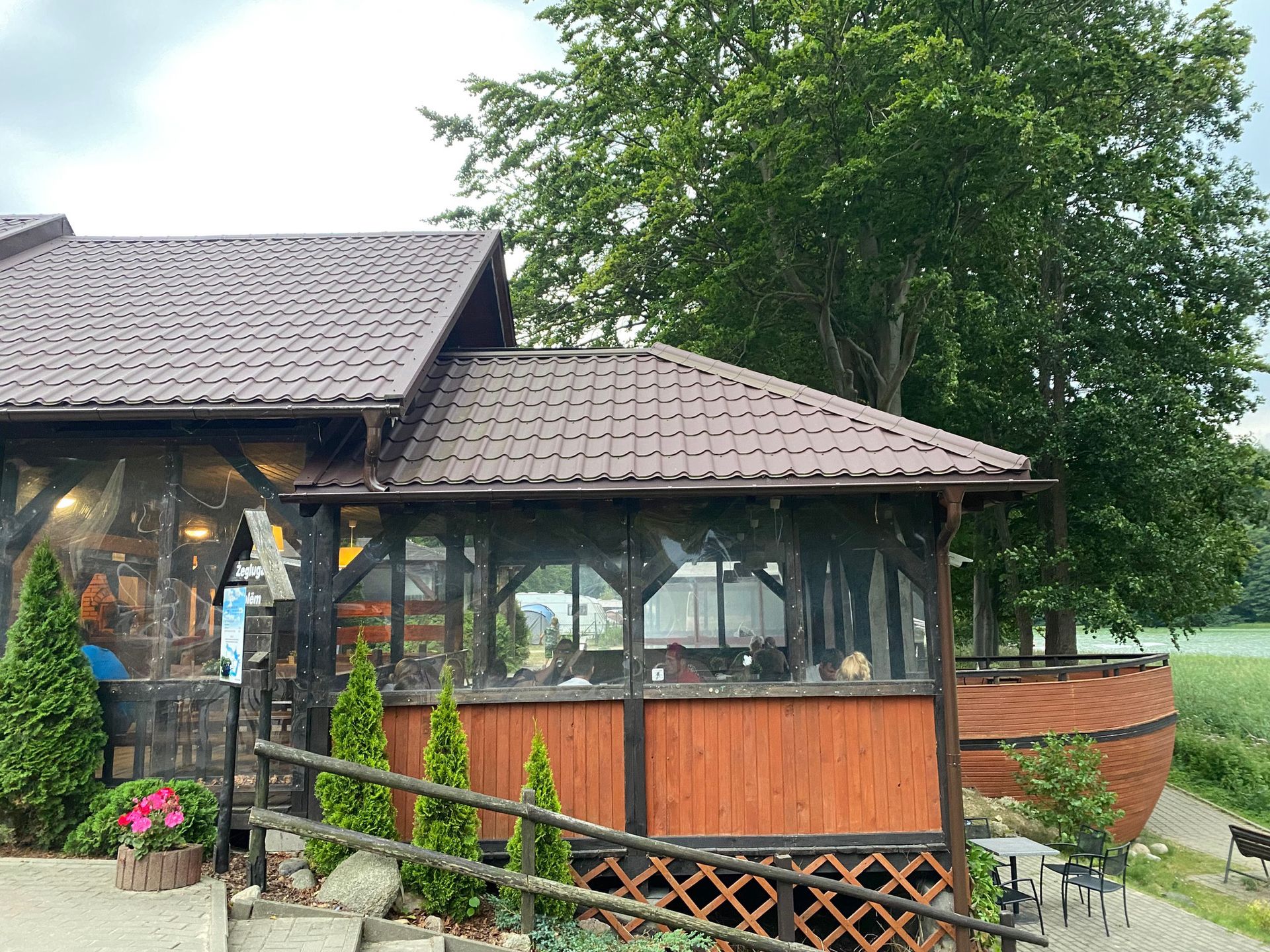 Biwakowicze chowają się przed deszczem pod dachem restauracji 