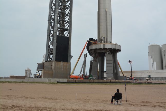 Fan przygląda się ostatnim pracom nad pierwszym stopniem (boosterem SuperHeavy) rakiety Starship, zdjęcie z 19.04.2023 r.