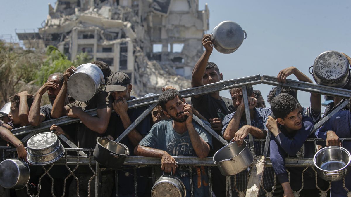 Czekający na pomoc humanitarną Palestyńczycy na tle ruin