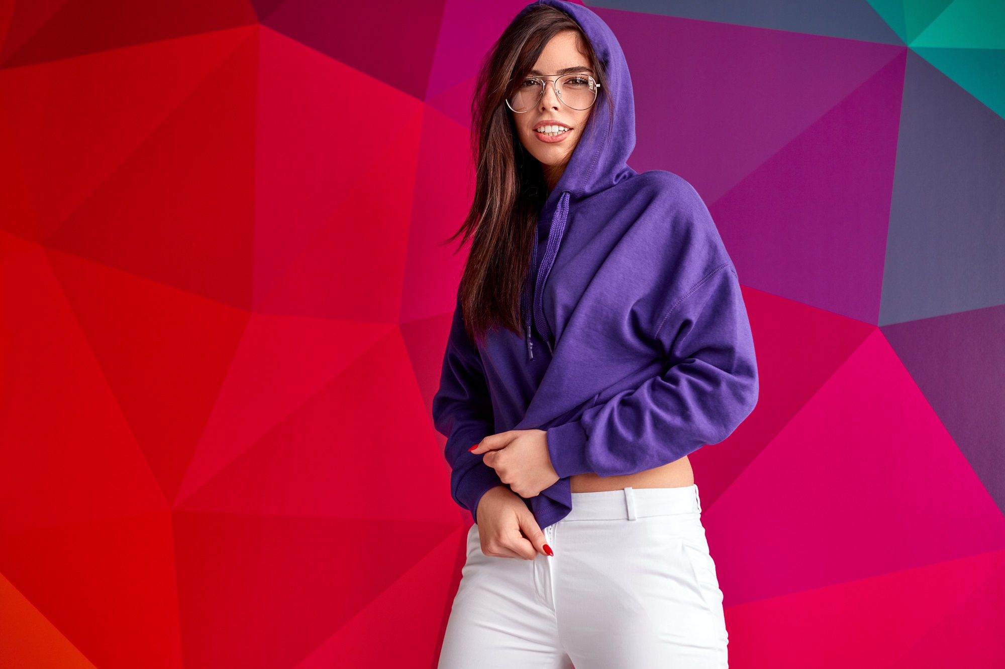 Young woman in trendy hoodiePretty young female in stylish glasses and violet hoodie looking at camera and smiling while standing against multicolored geometric backgroundwoman, urban, style, hoodie, glasses, smile, young, colorful, vibrant, geometric, female, hipster, model, outfit, cool, spectacles, eyewear, accessory, garment, clothing, lady, multicolored, abstract, fashion, casual, slim, trendy, cheerful, happy, joy, wear, beautiful, attractive, pretty, bright, vivid, horizontal, studio shot, looking at camera, copy space, woman, urban, style, hoodie, glasses, smile, young, colorful, vibrant, geometric, female, hipster, model, outfit, cool, spectacles, eyewear, accessory, garment, clothing, lady, multicolored, abstract, fashion, casual, slim, trendy, cheerful, happy, joy, wear, beautiful, attractive, pretty, bright, vivid, horizontal, studio shot, looking at camera, copy space
