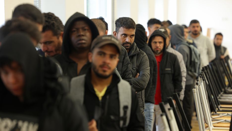 EISENHUETTENSTADT, GERMANY - OCTOBER 05: Men, many of them from Syria, queue for lunch at the initial reception facility for migrants and refugees on October 05, 2023 in Eisenhuettenstadt, Germany. The Eisenhuettenstadt facility serves as both a registration center and a temporary shelter for newly-arrived asylum seekers in the eastern state of Brandenburg. Germany is struggling to cope with a current large influx of migrants, mainly from Syria, Afghanistan and Turkey, arriving via Poland and the Czech Republic. (Photo by Sean Gallup/Getty Images)