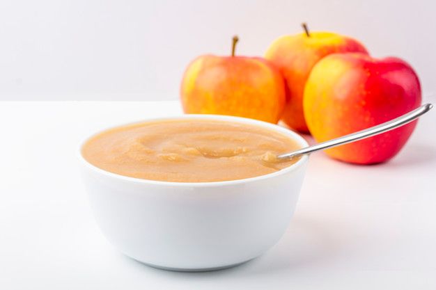 Fresh homemade applesauce. The concept of proper nutrition and healthy eating. Organic and vegetarian food. White bowl with fruit puree on fabric and apples on table. Baby food. Copy space for text