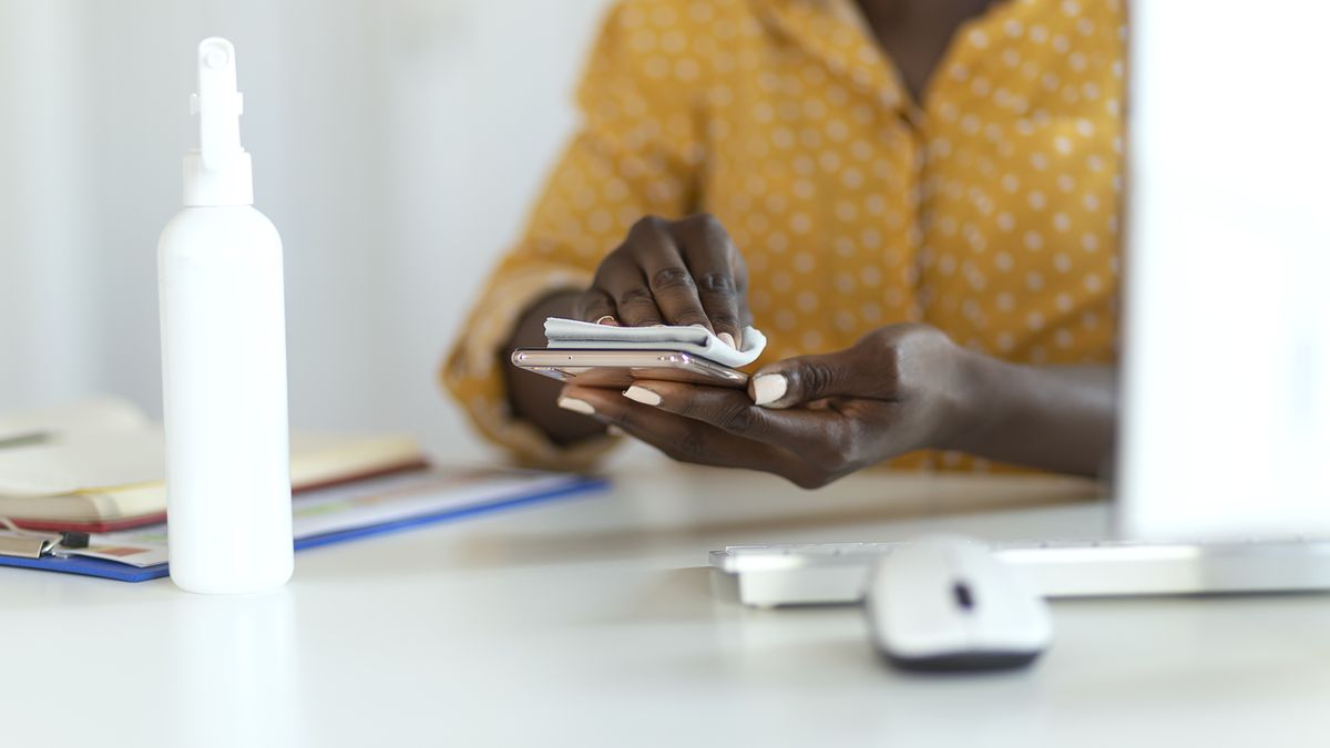 Disinfect, Sanitize, Hygiene Care. Cropped shot of African American Businesswoman Cleaning Fingerprint on Mobile Phone Touch Screen for Disinfection, Prevention of Germs Spreading During Infections of Covid-19 Coronavirus. Virus, germs, Bacteria That Are Frequently Touched