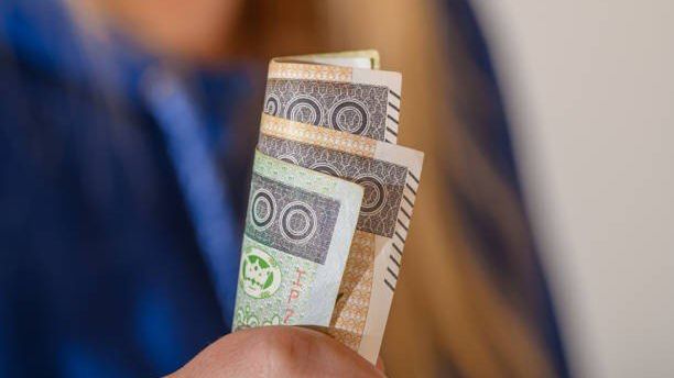 Woman shows money in her hand, cash in paper form, minimum wage