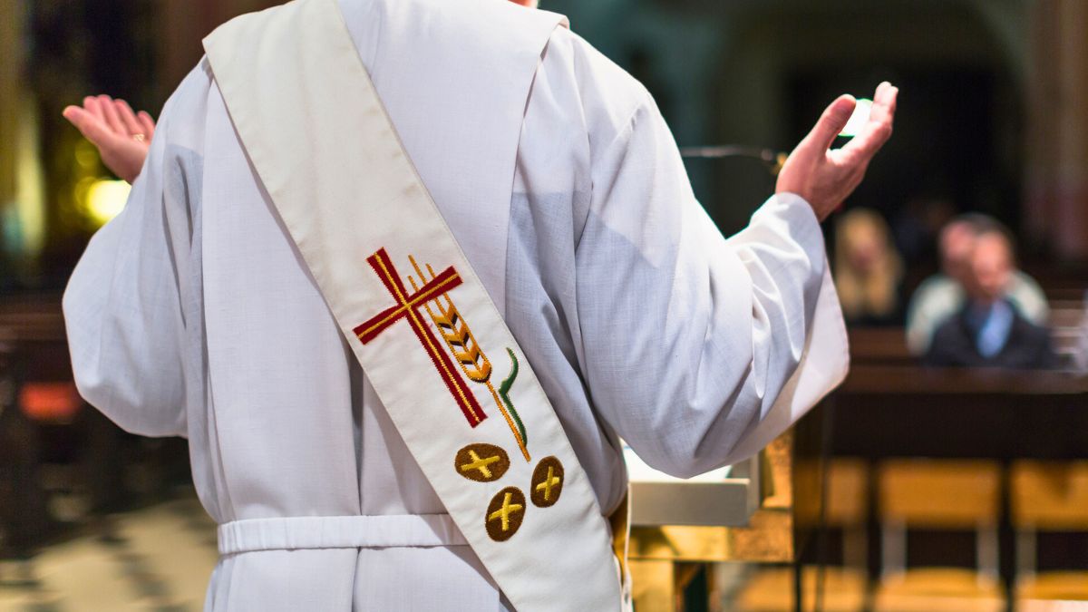 Ksiądz unosi ręce w kościele
